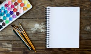 Blank notebook with watercolor palette on desk